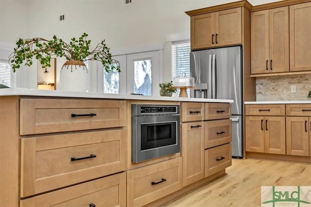 kitchen with stainless steel appliances, light hardwood / wood-style flooring, plenty of natural light, and decorative backsplash