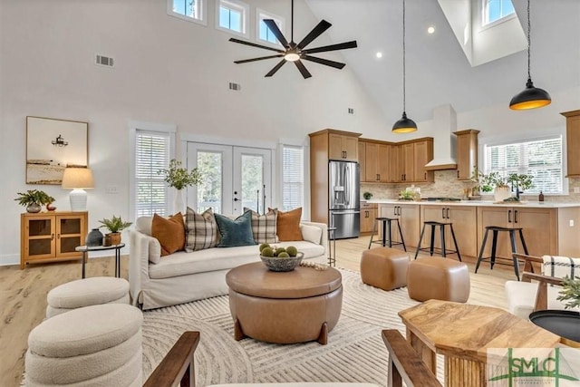 living room featuring high vaulted ceiling, light hardwood / wood-style flooring, and plenty of natural light