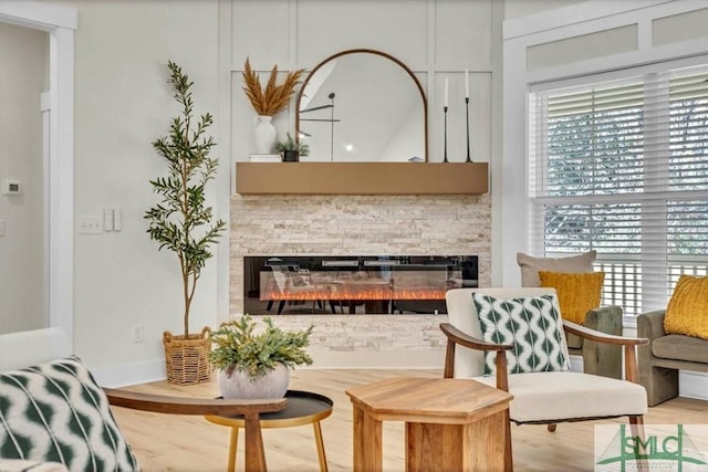 living area featuring hardwood / wood-style floors and a stone fireplace