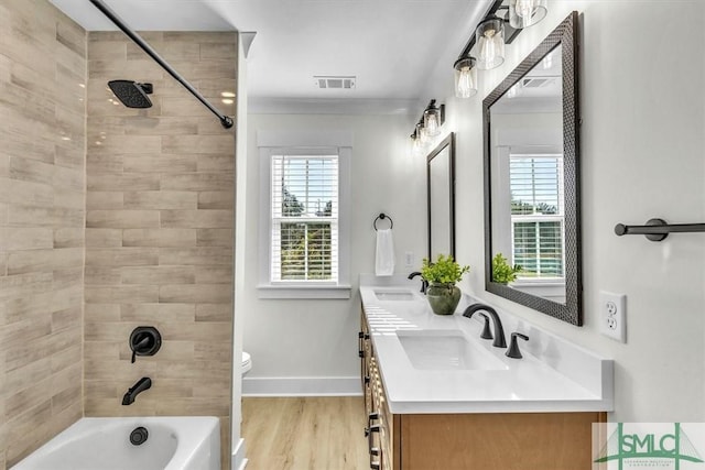 full bathroom with toilet, wood-type flooring, vanity, tiled shower / bath combo, and crown molding