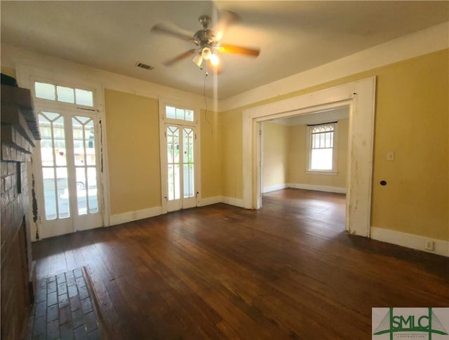 unfurnished room featuring ceiling fan, french doors, a fireplace, and dark wood-type flooring