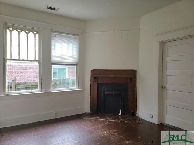 unfurnished living room featuring a wealth of natural light and dark hardwood / wood-style floors