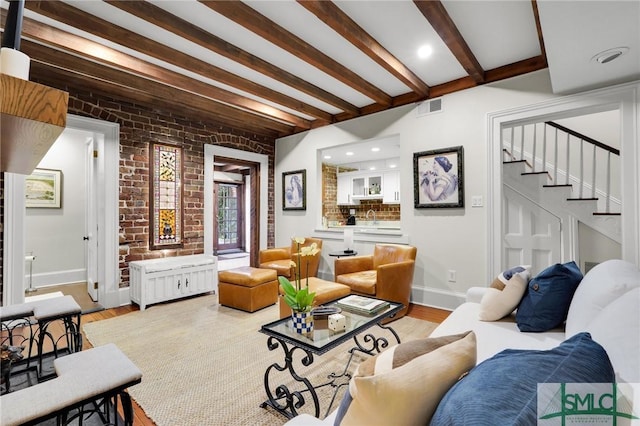 living room featuring beam ceiling, brick wall, and light hardwood / wood-style flooring