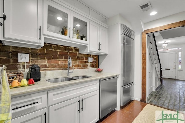 kitchen with white cabinets, appliances with stainless steel finishes, light stone counters, and sink