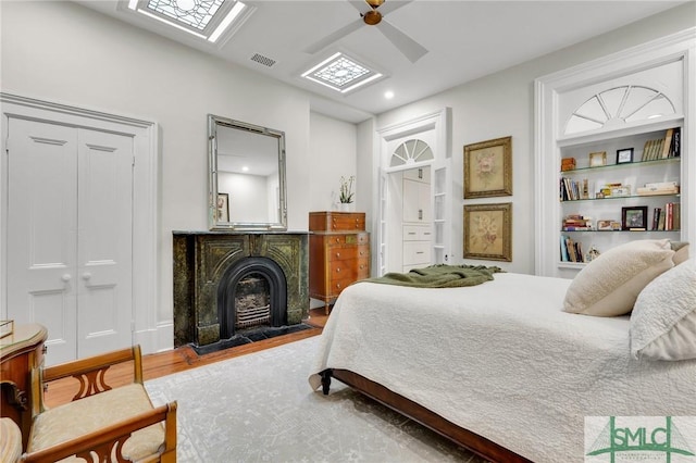 bedroom with wood-type flooring, a skylight, a closet, and ceiling fan