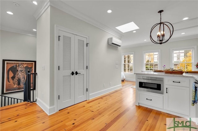 kitchen featuring white cabinets, hanging light fixtures, ornamental molding, a wall mounted AC, and a chandelier