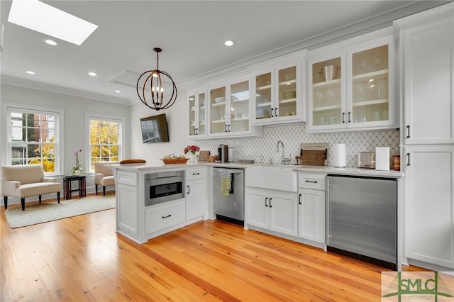 kitchen with refrigerator, a skylight, pendant lighting, dishwasher, and white cabinetry