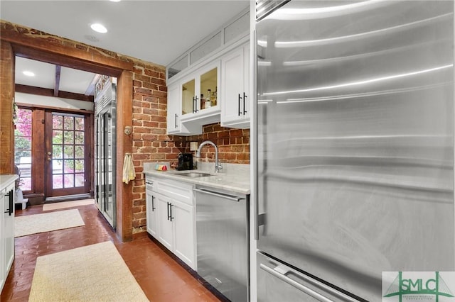 kitchen featuring white cabinets, appliances with stainless steel finishes, light stone counters, and sink