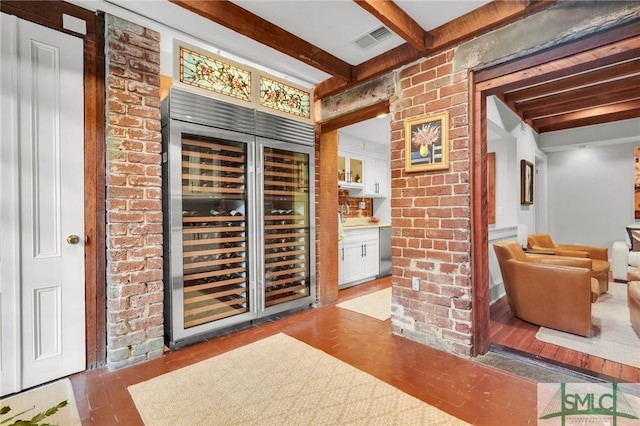 wine cellar with beamed ceiling, beverage cooler, and brick wall