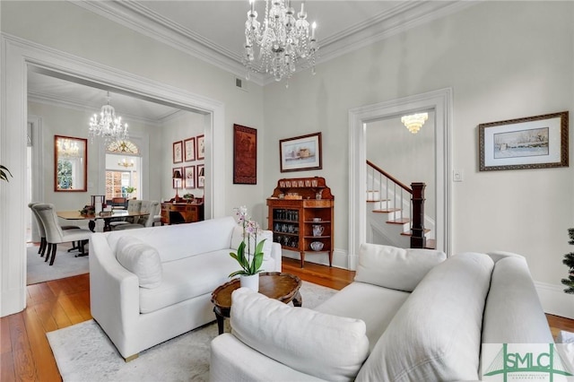 living room with a notable chandelier, light wood-type flooring, and ornamental molding