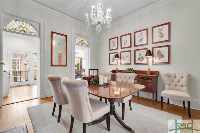 dining area with a chandelier, ornamental molding, light hardwood / wood-style floors, and a healthy amount of sunlight