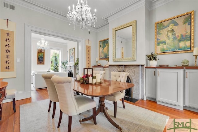 dining area featuring light hardwood / wood-style floors, crown molding, and an inviting chandelier