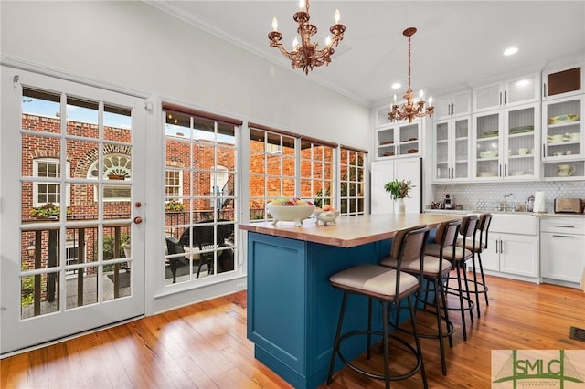 kitchen with pendant lighting, backsplash, an inviting chandelier, white cabinets, and a kitchen island