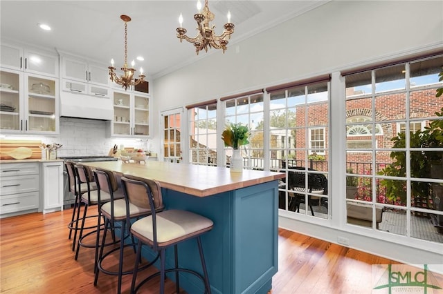 kitchen with pendant lighting, a center island, an inviting chandelier, stainless steel range oven, and white cabinetry