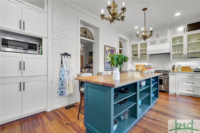 kitchen featuring white cabinetry, a center island, stainless steel appliances, an inviting chandelier, and premium range hood