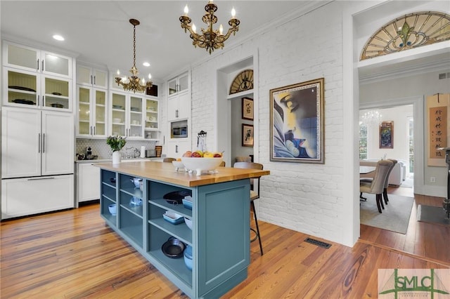 kitchen featuring blue cabinetry, white cabinetry, a center island, decorative light fixtures, and a breakfast bar area