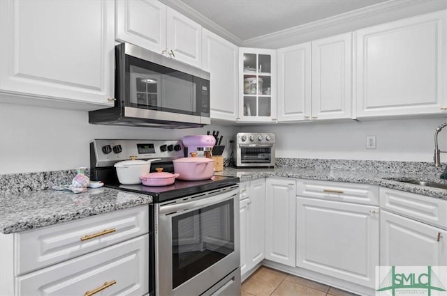 kitchen with appliances with stainless steel finishes, light tile patterned floors, white cabinetry, and sink