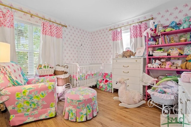 bedroom featuring a crib and light hardwood / wood-style floors