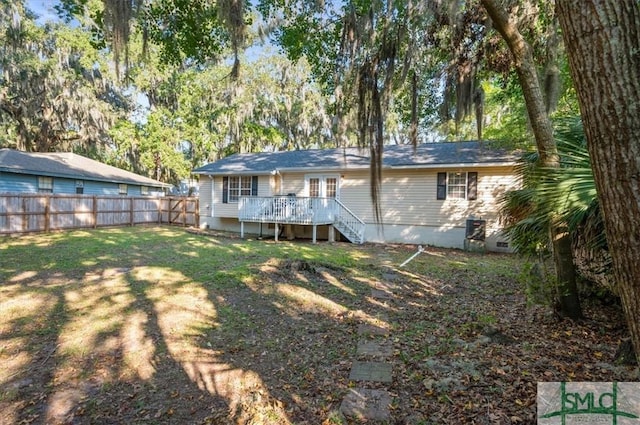 rear view of property featuring a lawn and a deck