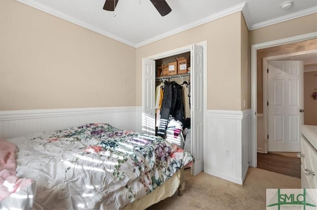 bedroom featuring ceiling fan, crown molding, light carpet, and a closet