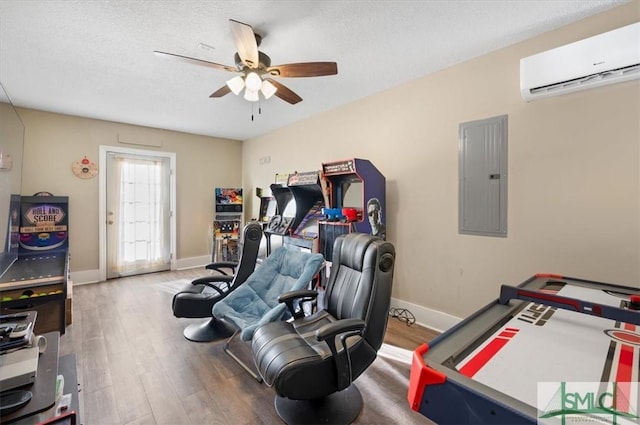 playroom with ceiling fan, electric panel, a wall mounted AC, a textured ceiling, and hardwood / wood-style flooring