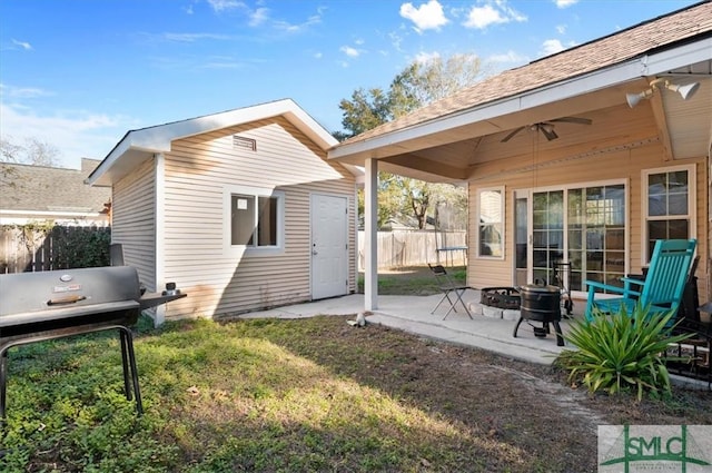 rear view of house with ceiling fan, a patio area, and a lawn