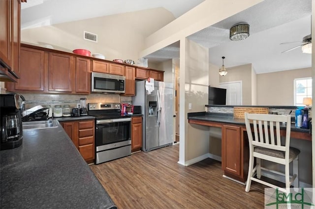 kitchen featuring decorative backsplash, dark hardwood / wood-style flooring, stainless steel appliances, ceiling fan, and pendant lighting