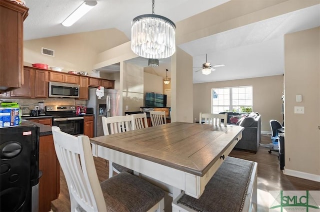 dining area with dark hardwood / wood-style flooring, ceiling fan with notable chandelier, and lofted ceiling