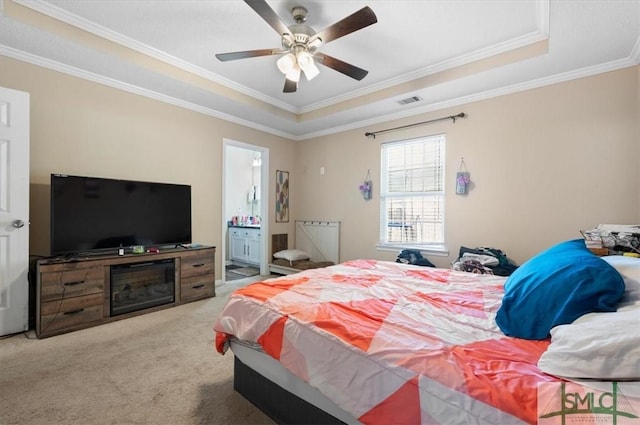 bedroom with connected bathroom, ceiling fan, light colored carpet, a tray ceiling, and ornamental molding