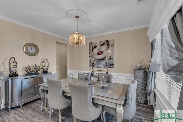 dining area featuring hardwood / wood-style floors, an inviting chandelier, and ornamental molding