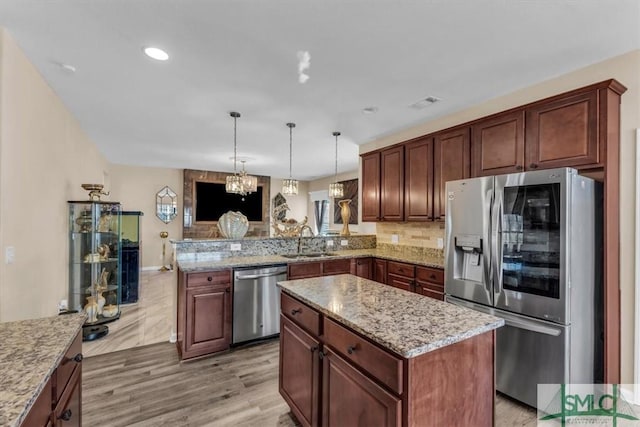 kitchen with decorative light fixtures, a kitchen island, light hardwood / wood-style floors, sink, and appliances with stainless steel finishes