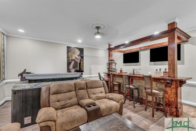 cinema room featuring light hardwood / wood-style flooring, bar, and crown molding