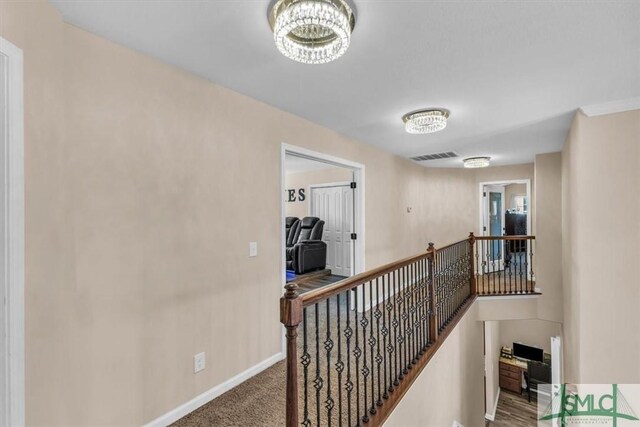 hallway featuring carpet flooring and a chandelier