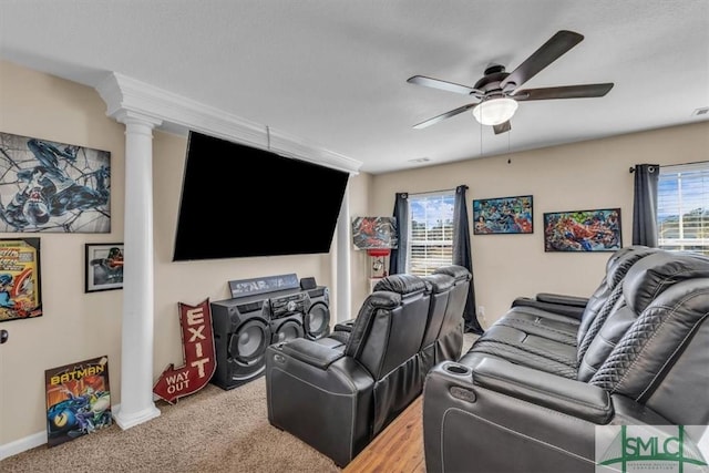 carpeted cinema room with decorative columns and ceiling fan