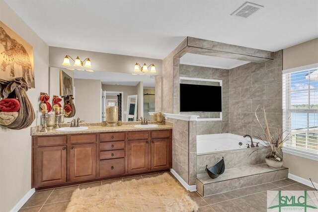 bathroom with tile patterned floors, vanity, and a relaxing tiled tub