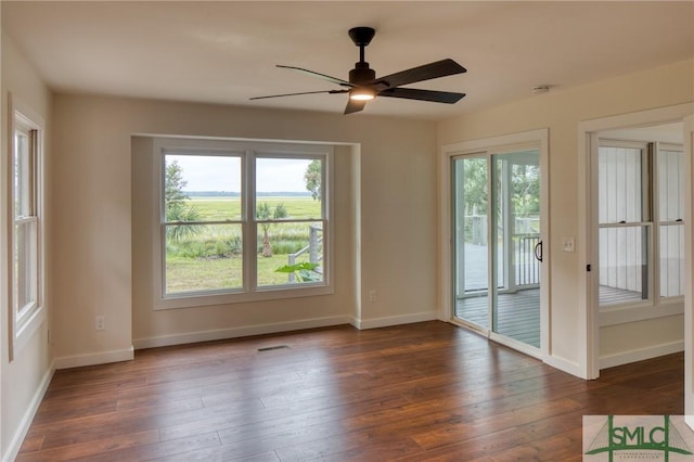 empty room with visible vents, a ceiling fan, hardwood / wood-style flooring, and baseboards