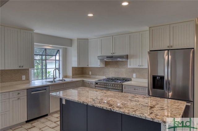 kitchen featuring appliances with stainless steel finishes, a center island, a sink, under cabinet range hood, and backsplash