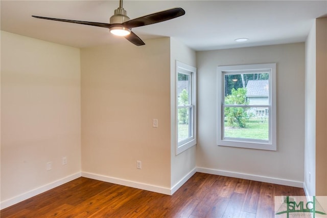 spare room with dark wood-style floors, baseboards, and a ceiling fan