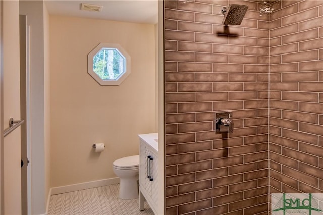 bathroom featuring toilet, visible vents, baseboards, a tile shower, and tile patterned floors