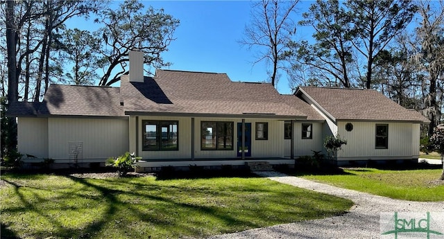 back of property with a porch, a lawn, a chimney, and a shingled roof