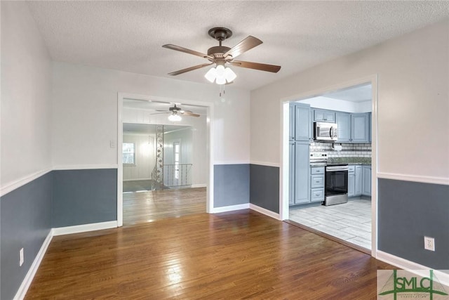 empty room with ceiling fan, light hardwood / wood-style flooring, and a textured ceiling