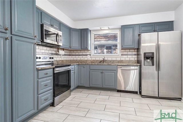 kitchen with backsplash, dark stone countertops, sink, and appliances with stainless steel finishes