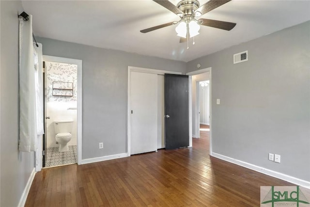 unfurnished bedroom with connected bathroom, ceiling fan, a closet, and dark hardwood / wood-style floors