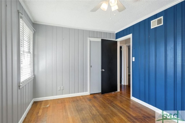 unfurnished room featuring ceiling fan, dark hardwood / wood-style floors, ornamental molding, and a textured ceiling