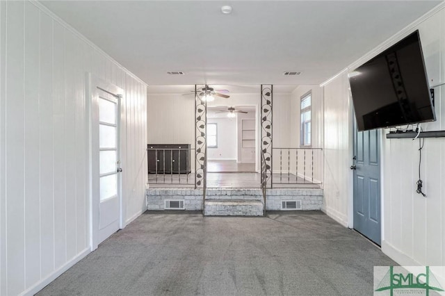 unfurnished living room with crown molding, carpet floors, and ceiling fan