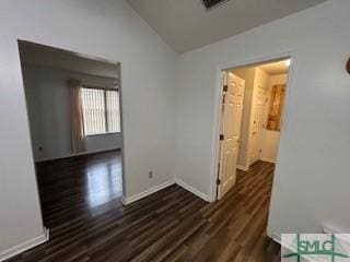 corridor with dark hardwood / wood-style flooring and lofted ceiling