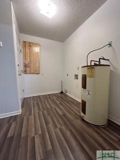 clothes washing area featuring electric water heater, dark wood-type flooring, and a textured ceiling