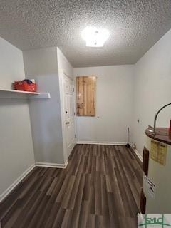 washroom with a textured ceiling, electric water heater, and dark wood-type flooring