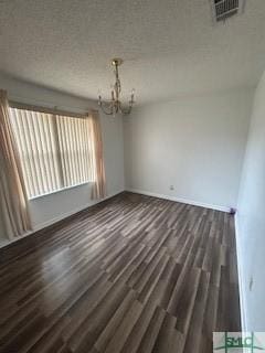 spare room featuring dark hardwood / wood-style floors and a chandelier