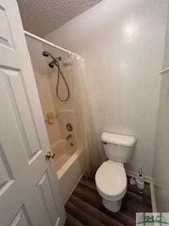 bathroom featuring hardwood / wood-style floors, a textured ceiling, toilet, and shower / washtub combination